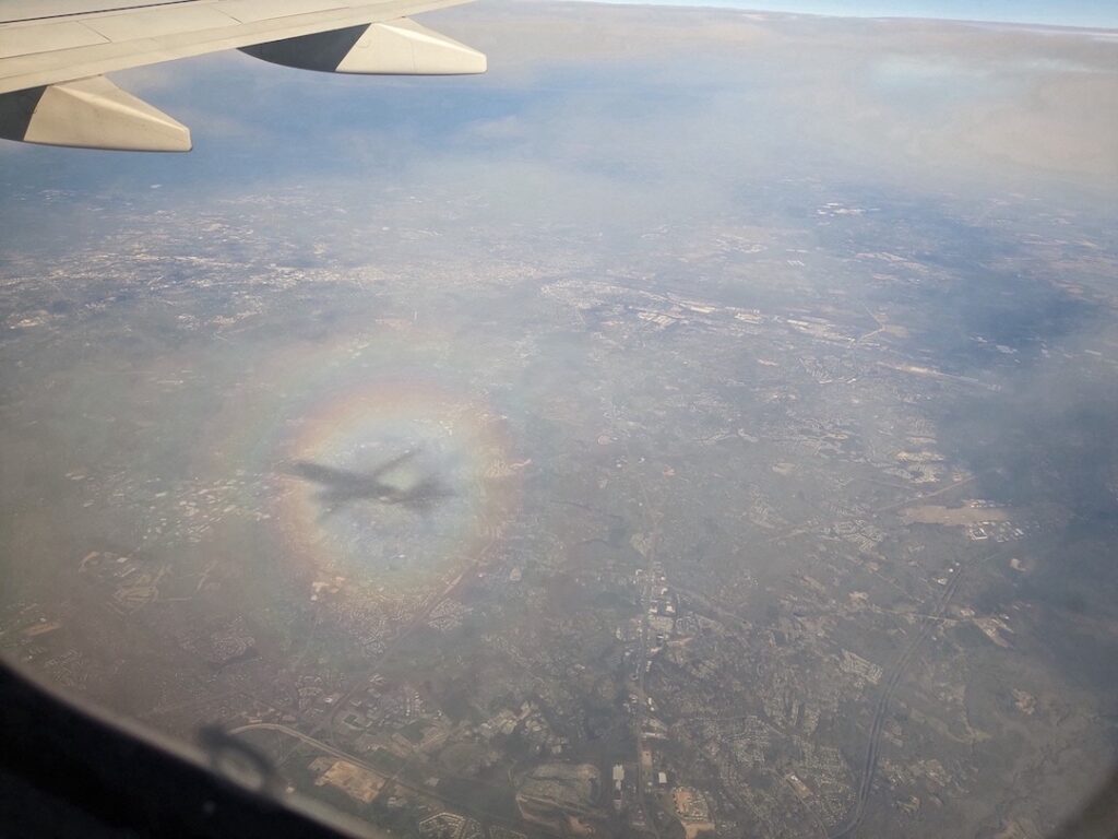 plane shadow in rainbow circle on clouds